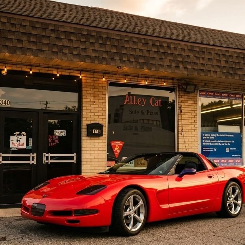 A red sports car parked in front of Alley Cat restaurant, a brick building with large windows.