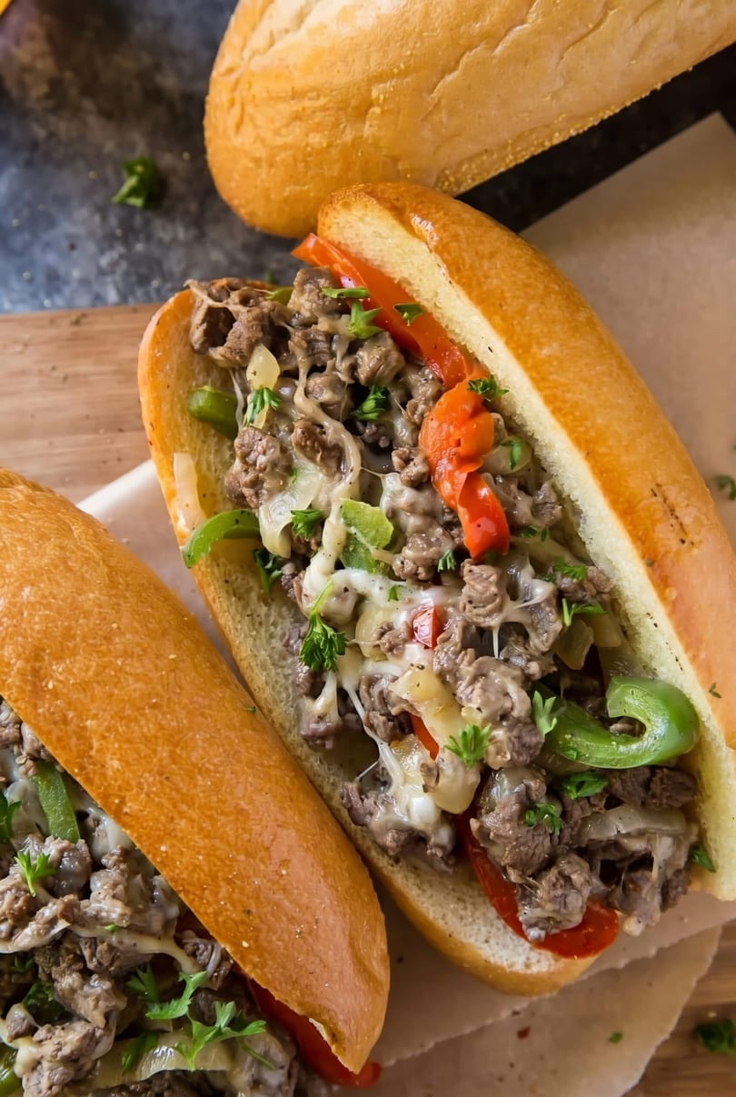 Two delicious Philly cheesesteak sandwiches with steak, melted cheese, peppers, and onions.